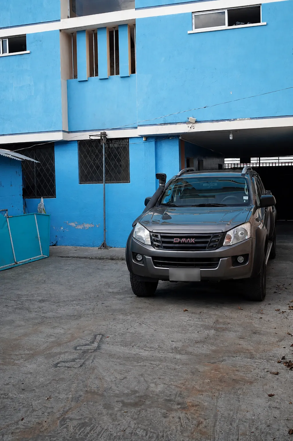 Camioneta estacionada en el garaje, junto a la pared azul del edificio