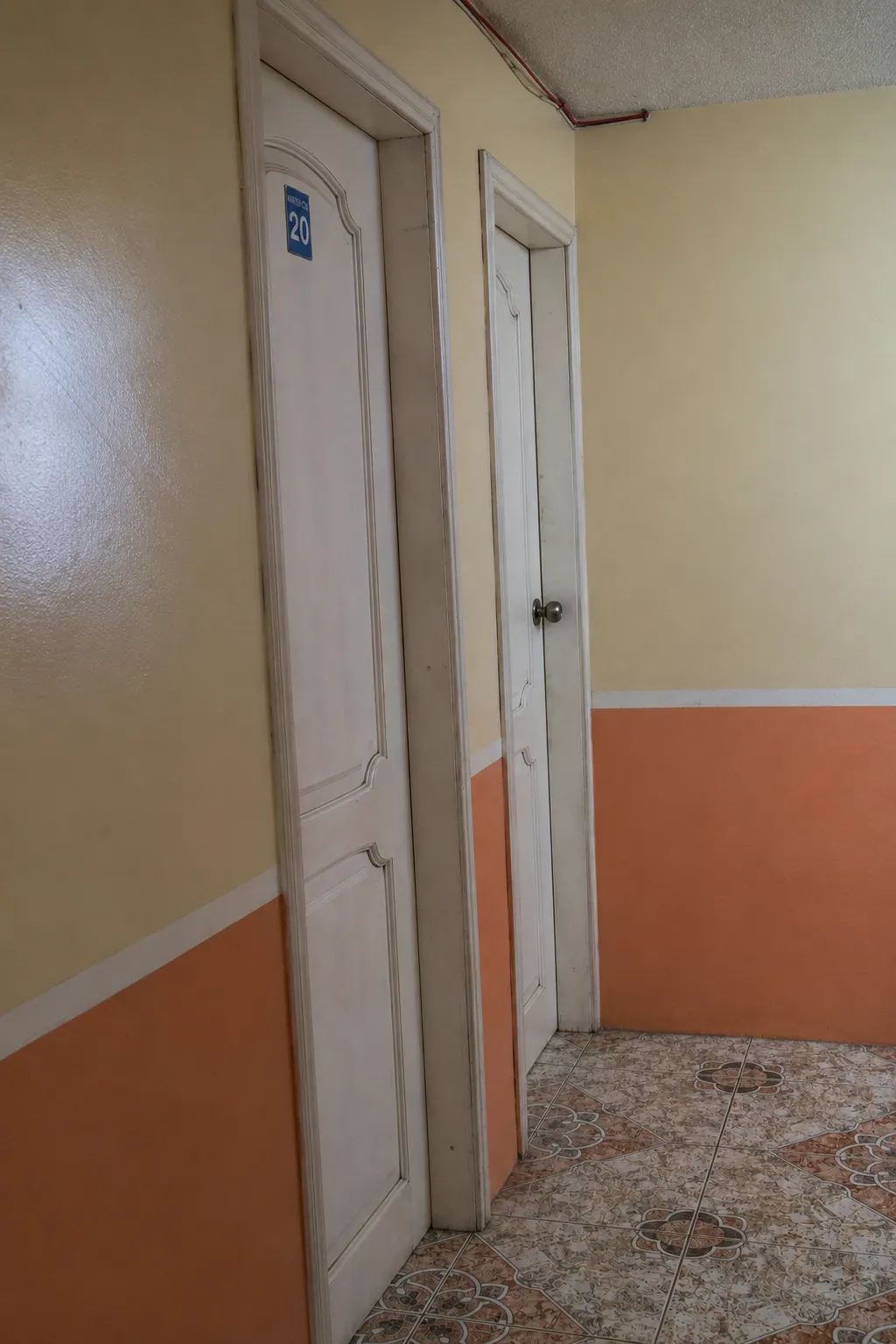 Pasillo crema y terracota con la placa de la habitación 20